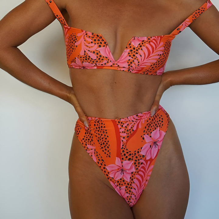 Gros plan sur le haut d'un bikini orange vif à imprimé floral rose et motifs léopard noirs. Idéal pour l'été, la plage et les vacances ensoleillées. Mode féminine, vêtements de plage.