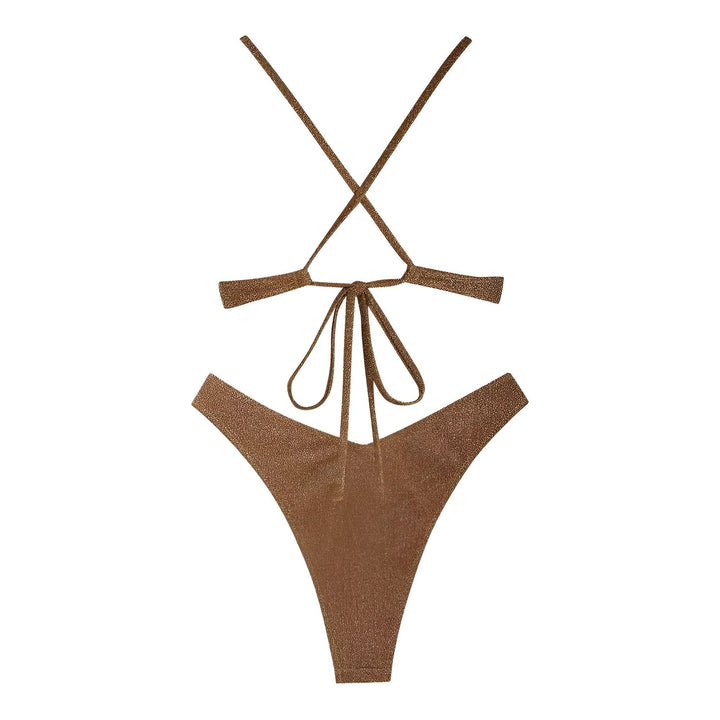 Portrait d'une jeune femme portant un bikini scintillant marron. Elle porte un collier papillon argenté. Elle se tient près d'une porte blanche avec une végétation luxuriante en arrière-plan.