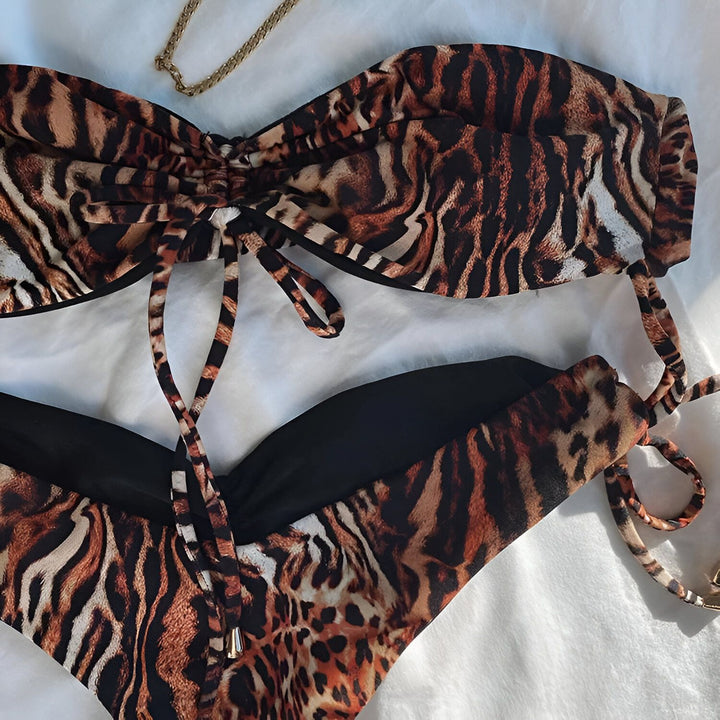 Gros plan d'une femme portant un bikini bandeau à imprimé léopard avec des liens à nouer, accentuant sa peau bronzée et ses tatouages. Mode estivale, détails du maillot de bain.