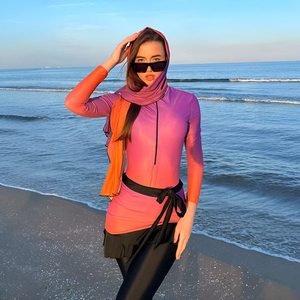Femme portant un burkini coloré et des lunettes de soleil sur la plage. Paysage marin avec ciel bleu et eau scintillante en arrière-plan. Mode de bain modeste.