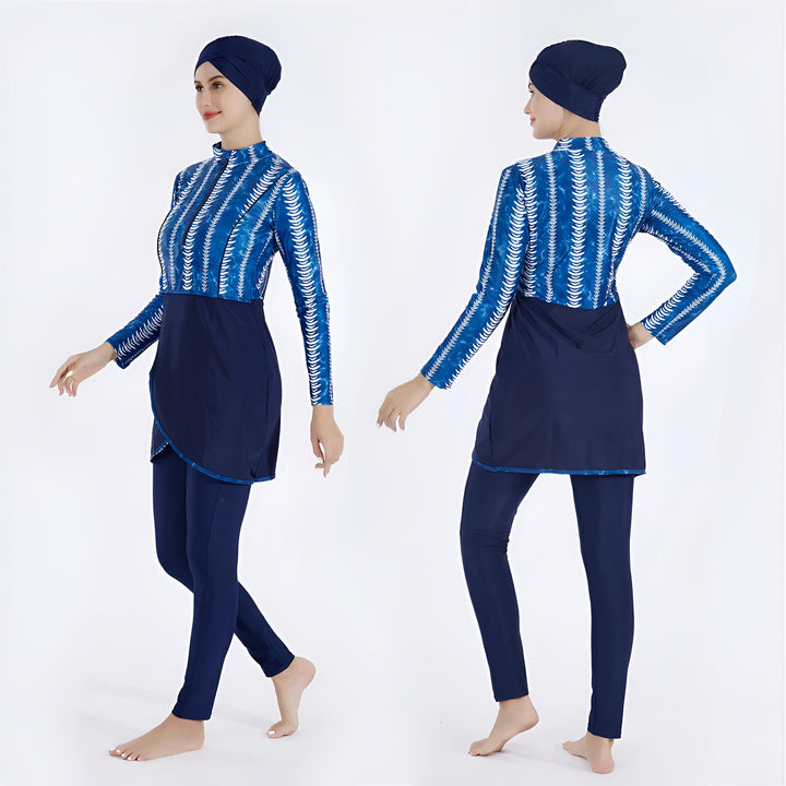 Femme portant un maillot de bain burkini bleu à manches longues avec un imprimé ondulé blanc. Le maillot a une jupe bleue marine et un legging assorti. Mode de bain islamique, vêtements de plage pudiques.