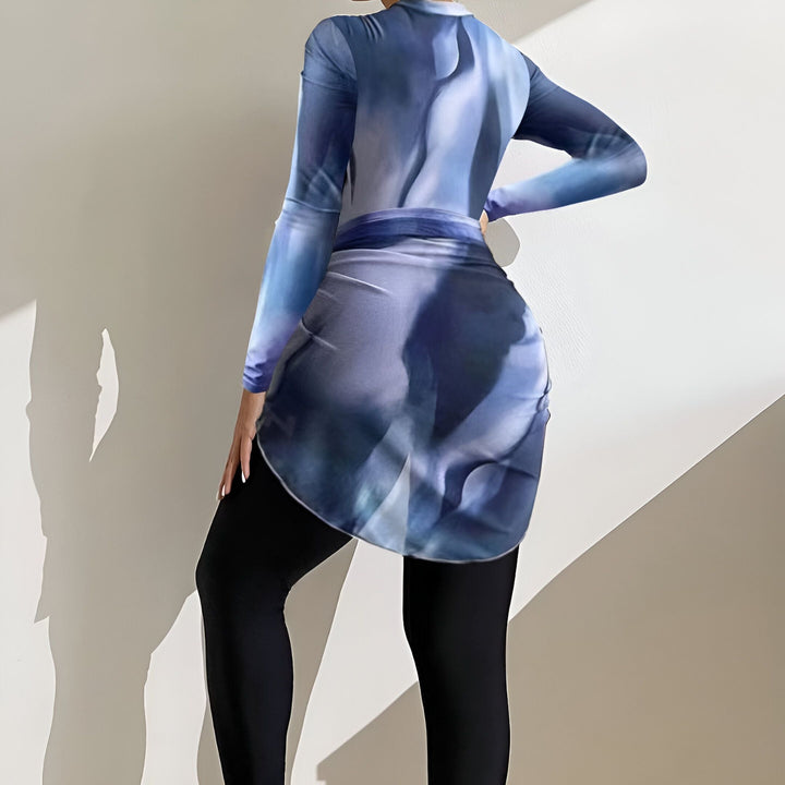 Vue arrière d'un maillot de bain couvrant à manches longues et une jupe courte imprimée bleue et noire, porté avec des leggings noirs. Idéal pour la natation modeste et la protection solaire.