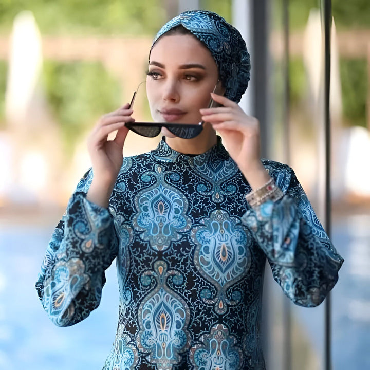 Femme portant une tunique de bain couvrante bleue à motifs orientaux. Idéal pour la baignade respectant les traditions. Mode islamique, vêtement de plage modeste.