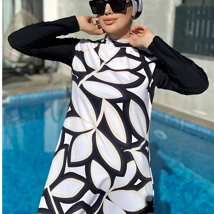 Femme portant un burkini à motif floral noir et blanc, lunettes de soleil et hijab près d'une piscine.