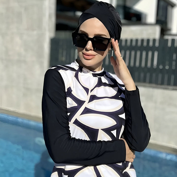 Femme portant un burkini noir et blanc à motifs floraux près d'une piscine. Vêtements de bain islamiques pour femmes.