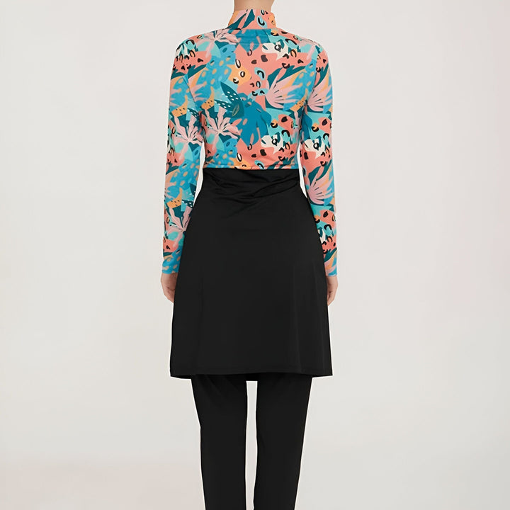 Maillot de bain modeste turquoise et corail à motifs floraux, haut à manches longues et bas noir, porté par une femme sur fond blanc.