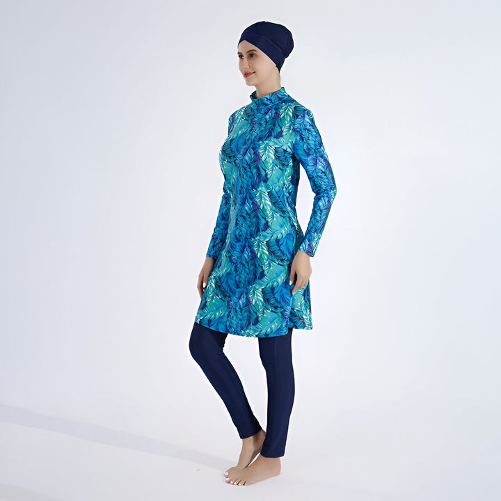 Maillot de bain burkini bleu turquoise avec motif de feuilles. Comprend un bonnet de bain, une tunique à manches longues et un legging, offrant une couverture complète pour les femmes musulmanes. Idéal pour la natation et les activités aquatiques.