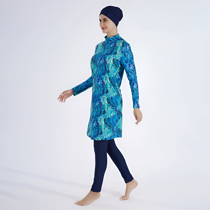 Femme portant un burkini bleu à motifs floraux, bonnet de bain assorti. Vêtement de bain modeste, mode islamique.