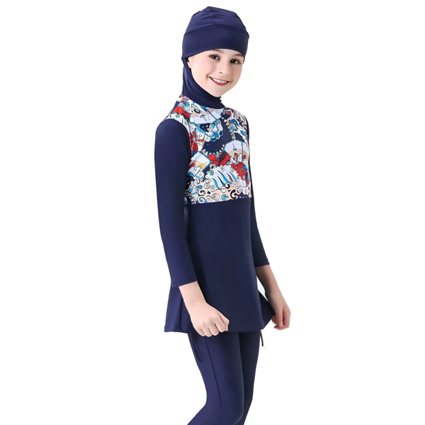 Une jeune fille portant un maillot de bain intégral bleu marine avec un motif coloré sur le haut, posant devant un fond blanc. Combinaison de bain islamique pour enfant.