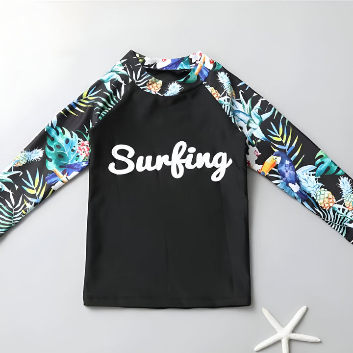 Ensemble de bain pour enfant, composé d'un haut à manches longues "Surfing", d'un short et d'un legging noir avec des motifs tropicaux, coquillage et étoile de mer.