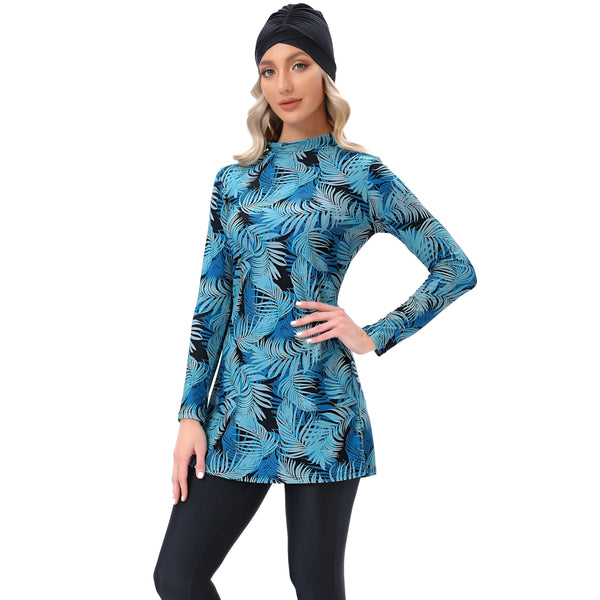 Femme portant un burkini imprimé feuilles bleues et noires, manches longues et col montant, associé à un legging noir. Mode pudique et tendance.
