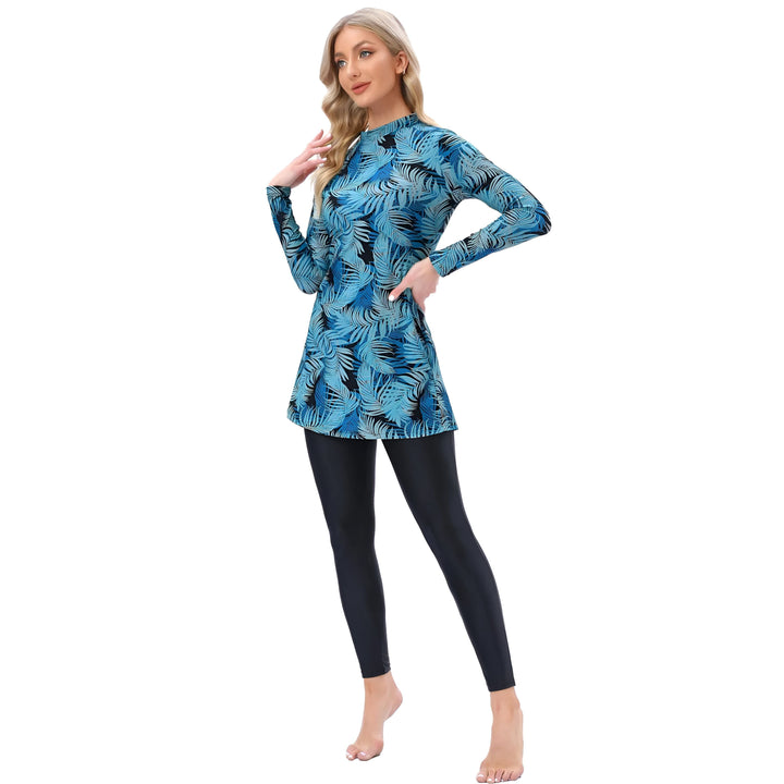 Une femme blonde portant un maillot de bain burkini bleu à motifs de feuilles de palmier et un bonnet noir. Vêtements de bain islamiques pour femmes. Mode modeste pour la plage.