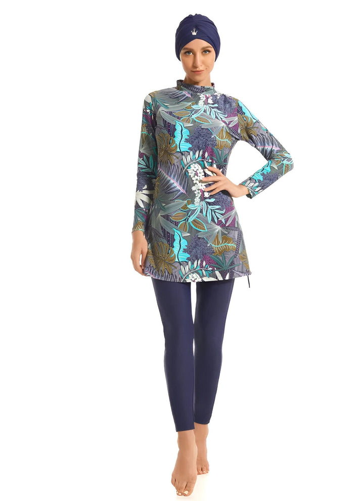 Femme portant un maillot de bain modeste à imprimé floral avec des leggings bleus marine, un style de vêtements de plage islamique à couverture complète.