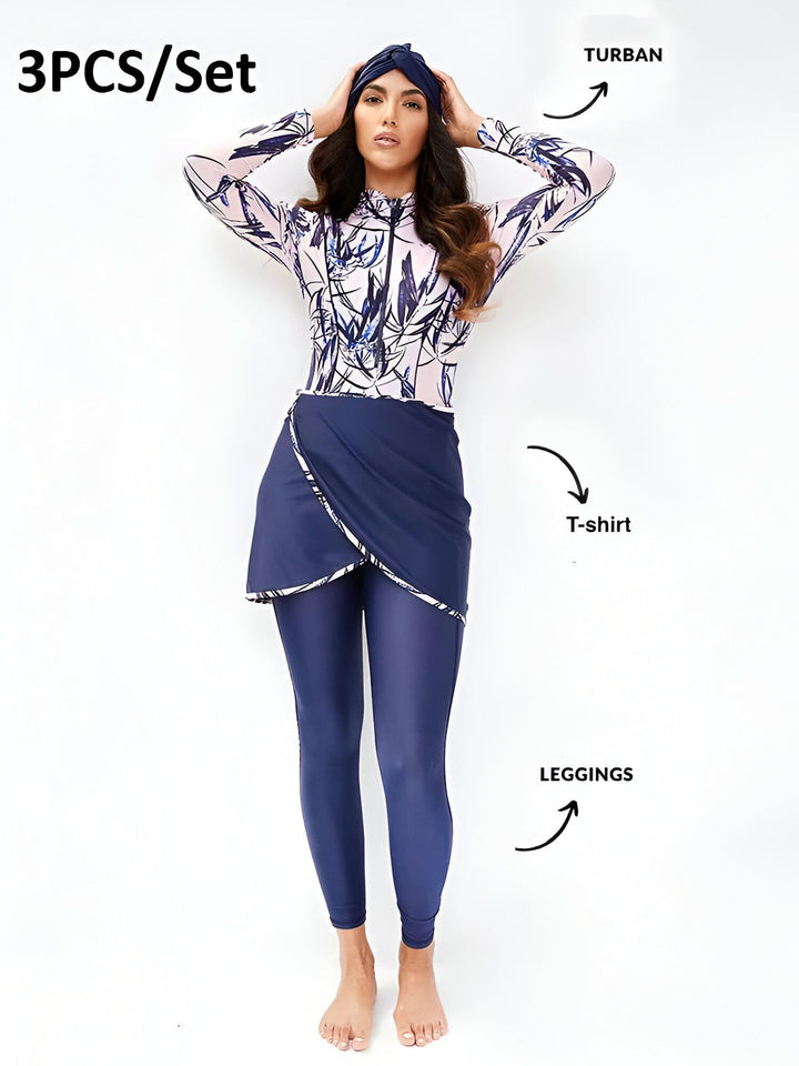 Femme portant un maillot de bain intégral gris et rose avec un turban, posant sur un fond blanc. Vêtement de bain de protection solaire avec manches longues et jupe drapée. Mode pudique, style islamique.