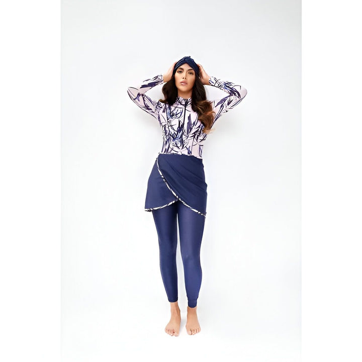 Femme portant un maillot de bain modeste noir avec un hijab et une jupe portefeuille assortie. Ses longs cheveux ondulés sont lâchés et elle pose les mains derrière la tête.