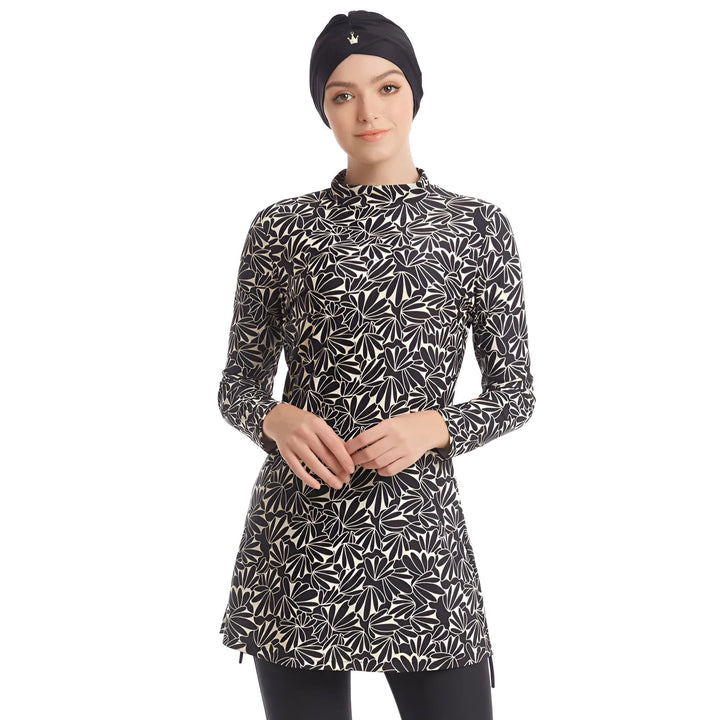 Vue arrière d'une femme portant un burkini noir et blanc à motifs floraux avec un bonnet de bain noir et un legging noir.