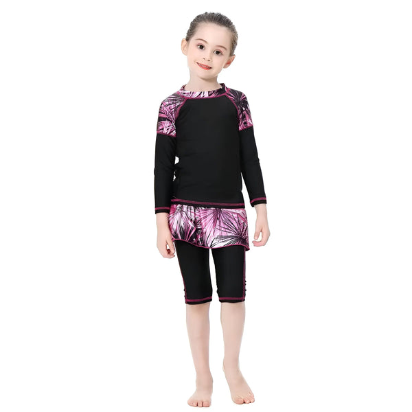 Une fillette souriante porte un maillot de bain intégral noir et rose avec un bonnet de bain assorti. Vêtement de bain couvrant pour enfant.