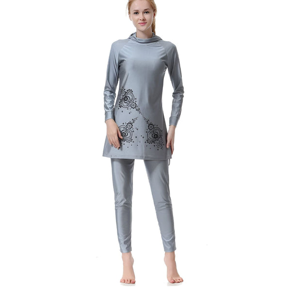 Vue arrière d'une femme portant un burkini gris, un maillot de bain couvrant avec capuche et pantalon long, idéal pour la pudeur et la protection solaire.