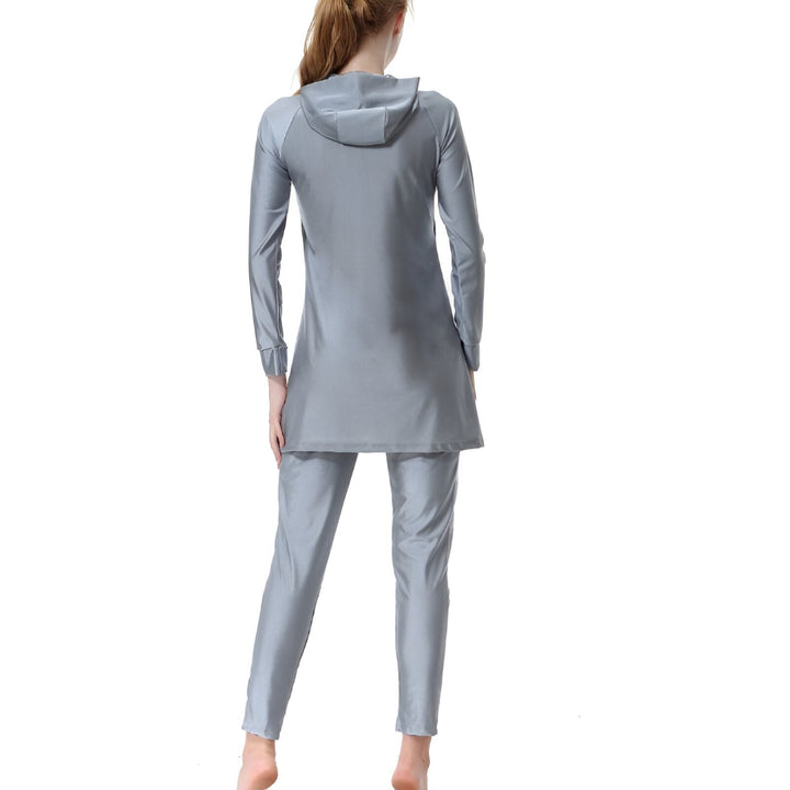 Femme portant un maillot de bain intégral gris avec capuche et motifs floraux noirs. Vêtement de bain modeste couvrant tout le corps, idéal pour la natation et les activités aquatiques avec une protection solaire.