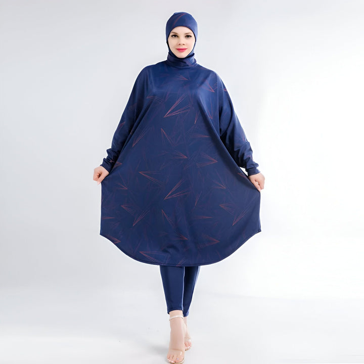 Femme portant un maillot de bain burkini bleu marine avec un motif géométrique rose. Le costume comprend un hijab, un haut à manches longues et un pantalon. Elle porte des talons hauts transparents.