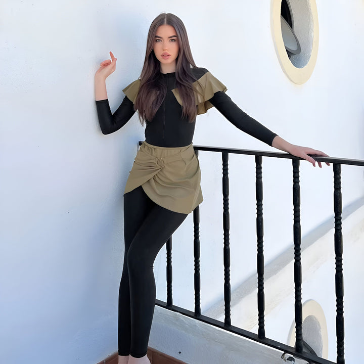 Jeune femme portant un maillot de bain long noir avec un volant vert olive sur les épaules et une jupe portefeuille assortie. Vêtement de plage tendance et élégant. Mode féminine pour l'été.