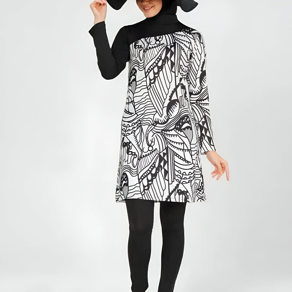 Femme portant un burkini noir et blanc à motifs, un legging noir et un chapeau noir à larges bords. Mode de bain pudique, vêtements islamiques pour femmes.