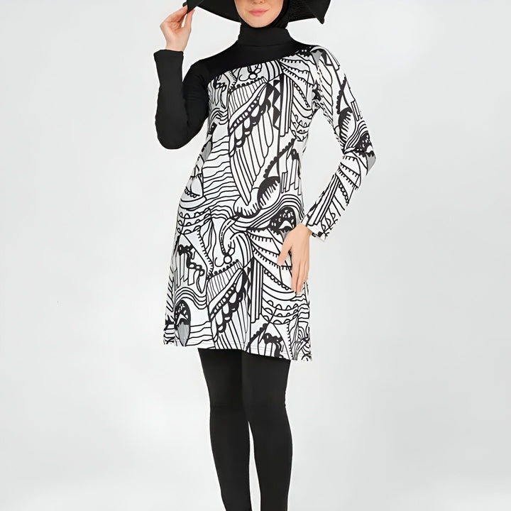 Femme souriante en burkini noir et blanc, avec un chapeau noir, devant un fond blanc. Maillot de bain islamique, vêtements de bain modestes pour femmes musulmanes. Mode féminine.