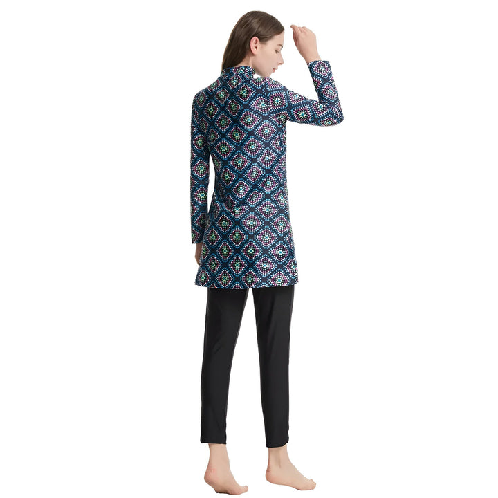 Femme vue de dos portant un maillot de bain couvrant à motifs géométriques colorés et un pantalon noir. Maillot de bain à manches longues, style modeste.