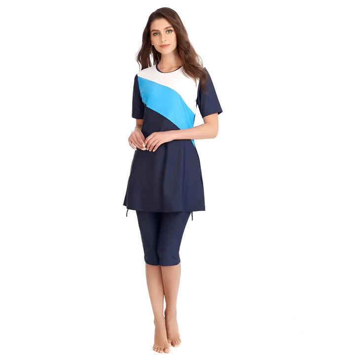 Femme portant un maillot de bain modeste bleu marine, blanc et bleu clair, avec un haut à manches courtes et un legging capri.