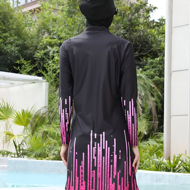 Vue arrière d'une femme portant un maillot de bain burkini noir avec un motif rose près d'une piscine. Le maillot de bain comprend un hijab assorti.