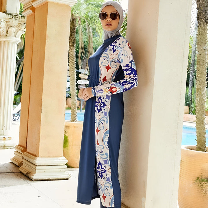 Vue arrière d'une femme portant un maillot de bain intégral bleu marine et blanc à motifs devant une piscine et des colonnes classiques.