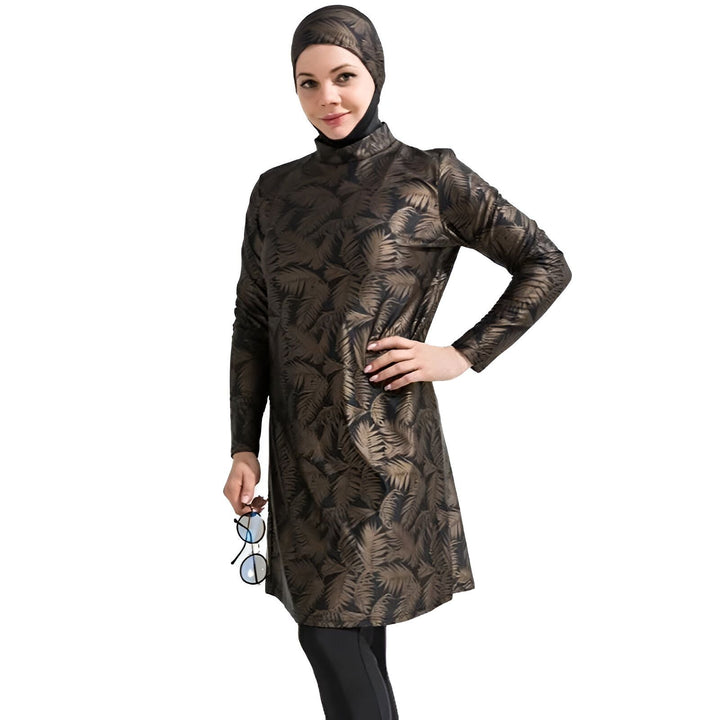 Femme portant un burkini imprimé de feuilles de palmier avec un hijab et des lunettes de soleil sur la tête, sur fond blanc.