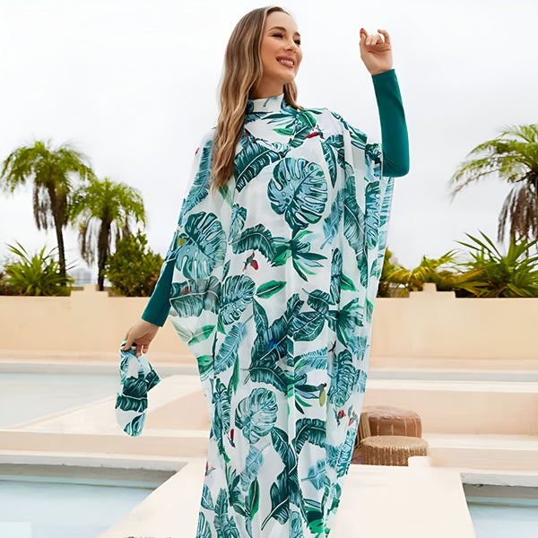 Femme portant une longue robe blanche à motifs de feuilles tropicales vertes près d'une piscine avec des palmiers en arrière-plan. Mode été, style tropical, vacances.