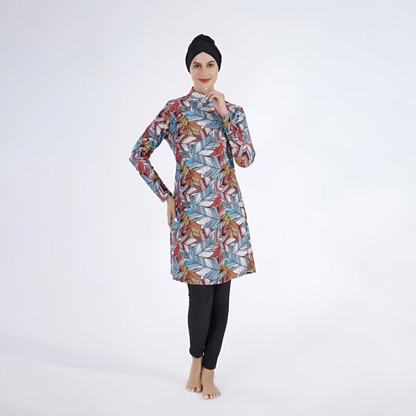 Femme portant un burkini imprimé feuilles colorées et un hijab noir, vêtement de bain couvrant, style modeste et élégant, look islamique.