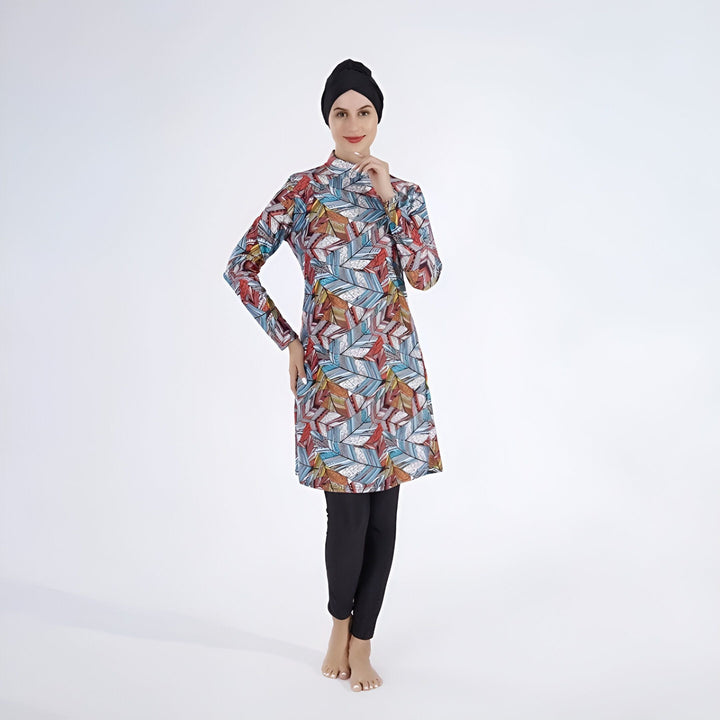 Femme portant un burkini imprimé feuilles colorées et un hijab noir, vêtement de bain couvrant, style modeste et élégant, look islamique.