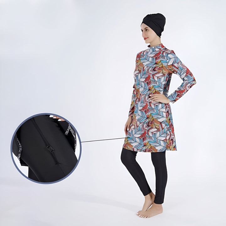 Femme portant un maillot de bain intégral avec un motif coloré et un hijab noir. Détail zoomé sur la fermeture éclair du maillot. Mode de bain pudique pour femmes musulmanes.