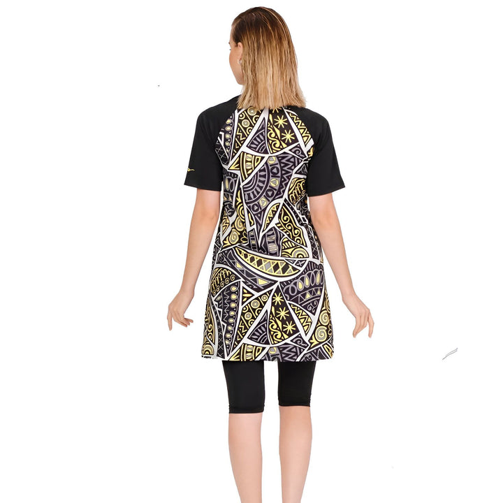 Femme portant un burkini moderne avec motif géométrique noir et or. Maillot de bain islamique couvrant avec manches courtes et leggings noirs. Mode pudique pour la natation.