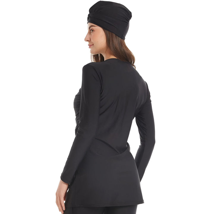 Femme portant un burkini noir avec un bonnet de bain assorti. Vêtement de bain intégral offrant une protection solaire. Style pudique et élégant. Mode islamique.