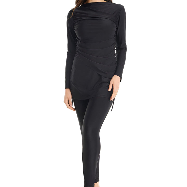 Femme souriante portant un burkini noir avec turban assorti, vêtement de bain couvrant pour la pudeur et la protection solaire. Vêtements de sport islamiques.