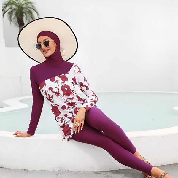 Femme portant un maillot de bain modeste violet et blanc à motifs floraux près d'une piscine turquoise et d'un palmier. Vêtements de bain islamiques, mode pudique.