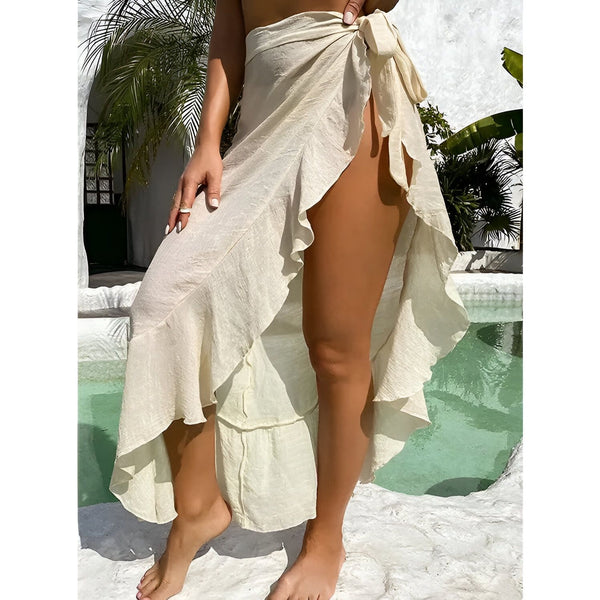 Femme portant un paréo blanc noué à la taille, devant une piscine turquoise. Vêtement d'été léger et élégant. Mode estivale, ambiance vacances.