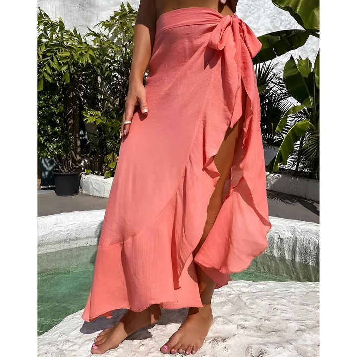 Une femme tenant un sac en bambou, portant un paréo blanc transparent près d'une piscine. Mode de plage, style estival, accessoires de vacances. Arrière-plan tropical avec des palmiers.