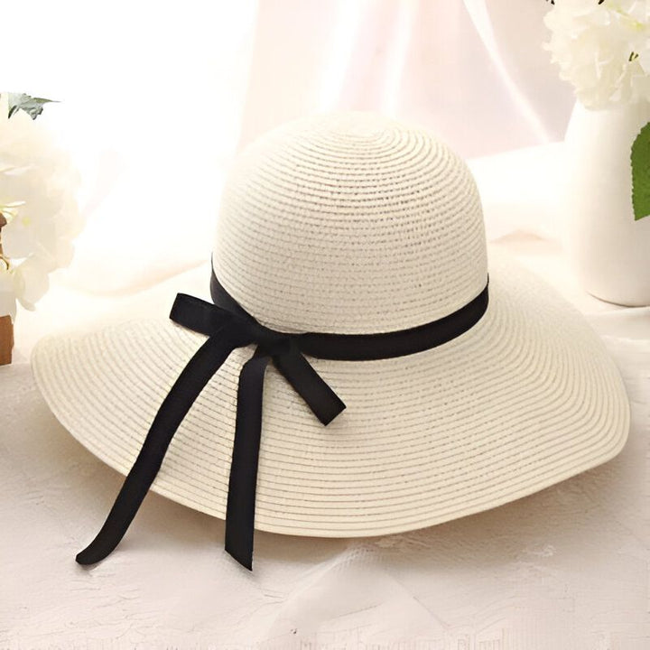 Chapeau de paille beige avec ruban noir, parfait pour l'été et la protection solaire. Élégant et décontracté, idéal pour la plage ou une promenade en ville.