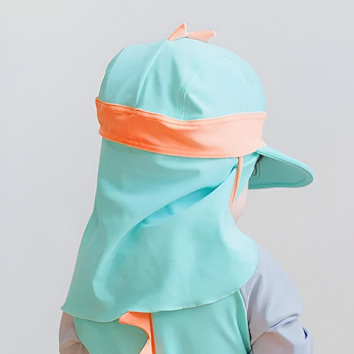 Enfant portant un chapeau de soleil bleu aqua avec une visière et une protection de cou, bordure orange. Vêtement de protection solaire pour enfants.