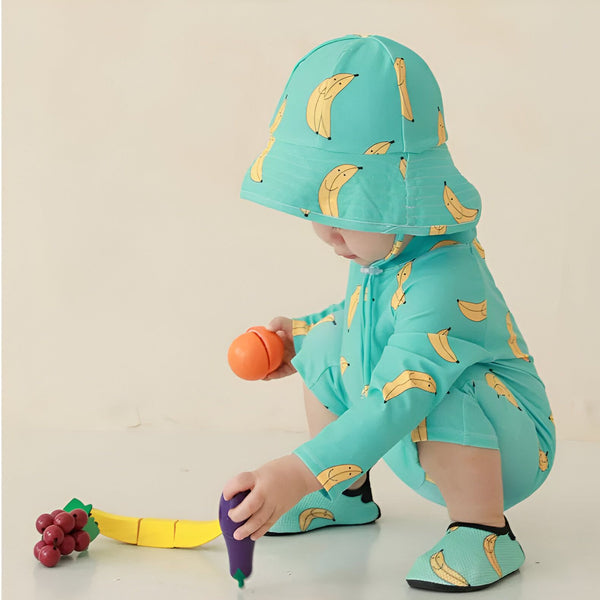 Combinaison de bain bébé beige à manches longues, imprimée avec des pêches roses souriantes avec des feuilles vertes. Fermeture éclair au col.