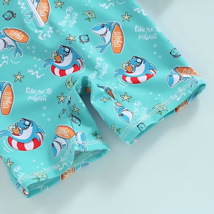 Combinaison de bain turquoise à manches longues pour enfant avec motifs de requins, bouée de sauvetage et planches de surf "Aloha". Accessoires de plage : bouée, étoile de mer, coquillages. Idéal pour la plage ou la piscine.