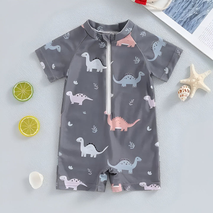 Gros plan d'un vêtement pour enfant gris imprimé avec des motifs de dinosaures de différentes couleurs et de petites feuilles. Idéal pour le thème de l'enfance ou de la mode enfantine.