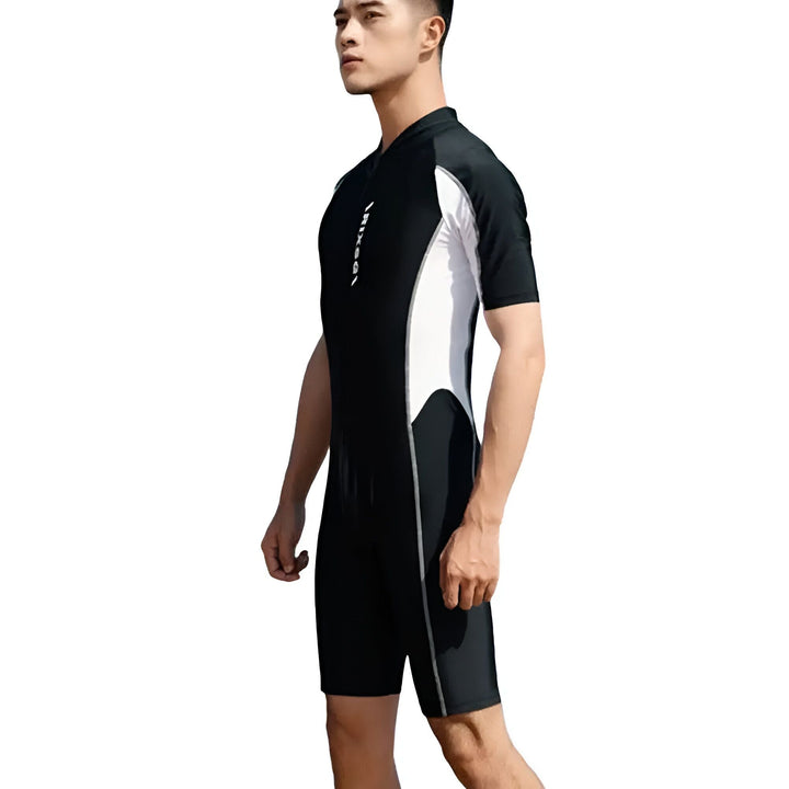 Homme portant un maillot de bain une pièce bleu marine et blanc avec fermeture éclair et lunettes de soleil.