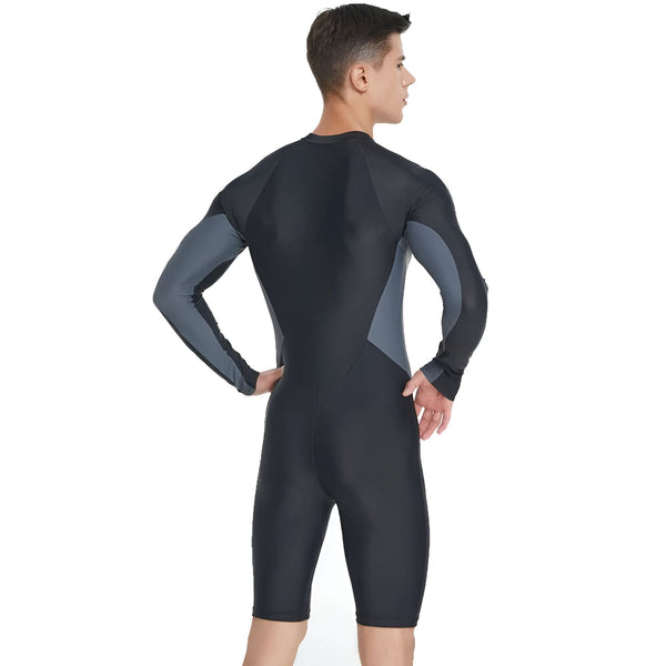 Un homme porte une combinaison de plongée noire à manches longues et aux jambes courtes. La combinaison porte le logo "Sbart" sur la poitrine et a des empiècements gris sur les côtés.