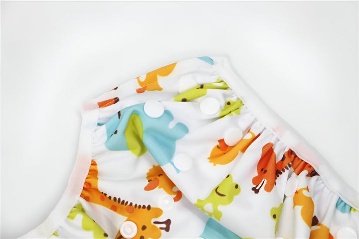 Détail d'une couche lavable blanche avec boutons pressions et étiquette d'entretien, montrant la texture du tissu et la bordure.